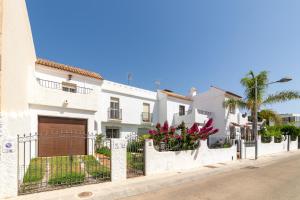 a white house with a gate and flowers on a street at Casa Rural La Buganvilla in Níjar