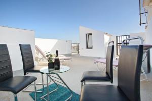 a patio with chairs and a table with a bottle of wine at Casa del Sol Rosa in Corralejo