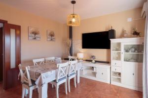 a dining room with a table and a flat screen tv at El Balcón de la Sierra in Seville