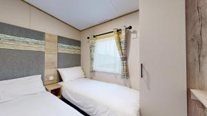 two beds in a small room with a window at Unity Seven Lakes in Crowle