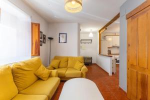 a living room with a yellow couch and a kitchen at De los Maestros in El Arenal
