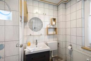 a white tiled bathroom with a sink and a mirror at Ferienwohnung Steffi in Laichingen +25 photos