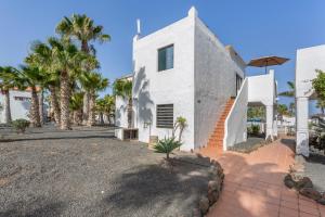 a white house with palm trees and a driveway at Brisa Azul in Corralejo
