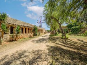 a dirt road in front of a building with a windmill at Possessio Sa Barrala Gallinero in Campos