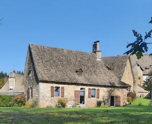 an old stone house with a gray roof at Maison de Vacances Chadirac in Auriac