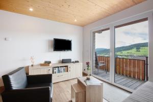 a living room with a television and a balcony at Ferienwohnung Blösling 2 in Bernau im Schwarzwald