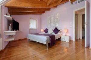 a bedroom with a bed with purple walls and wooden floors at Luxury Lakefront Maisonette in Lezzeno