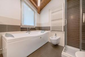 a bathroom with a tub and a sink and a toilet at Luxury Lakefront Maisonette in Lezzeno +16 photos
