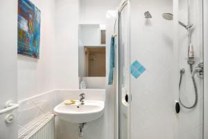 a white bathroom with a sink and a shower at room4you in Hemmingen +10 photos