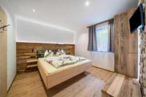 a bedroom with a bed with a wooden wall at Waldes Duft Apartment - Patleidhof in Naturno