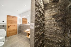 a bathroom with a stone wall and a shower at Waldes Duft Apartment - Patleidhof in Naturno +29 photos
