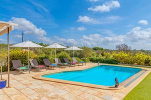 a swimming pool with chairs and umbrellas in a yard at Villa Gemma in Ses Salines