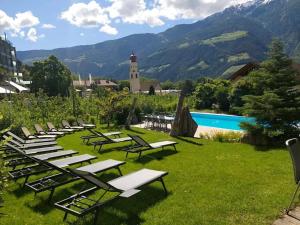 a row of lounge chairs and a pool with mountains at Garni Unterweggütl in Naturno