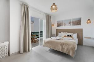 a white bedroom with a bed and a table at Sunlit Modern Stay in Arona