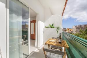 a balcony with a wooden table and glass doors at Sunlit Modern Stay in Arona