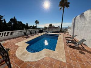 a swimming pool with chairs and a palm tree at Casa Montelado in Mijas