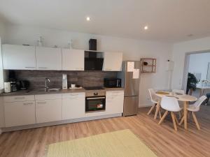 a kitchen with white cabinets and a table with chairs at Rike in Oesterdeichstrich