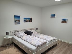 a bed in a white room with paintings on the wall at Rike in Oesterdeichstrich
