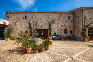 a large stone building with potted plants in a courtyard at Siesta del Sol in Manacor