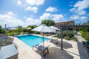 an outdoor swimming pool with an umbrella and two chairs and a table and an umbrella at Siesta del Sol in Manacor