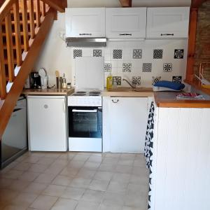 a kitchen with white cabinets and a stove at Gîte Du Recoux in Le Recoux +2 photos