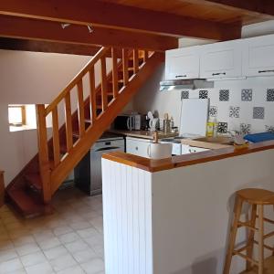 a kitchen with white cabinets and a staircase at Gîte Du Recoux in Le Recoux