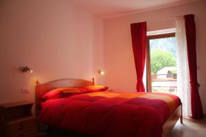 a bedroom with a bed with red curtains and a window at Da Lisi in Ugovizza