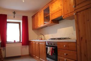 a kitchen with wooden cabinets and a stove and a window at Da Lisi in Ugovizza