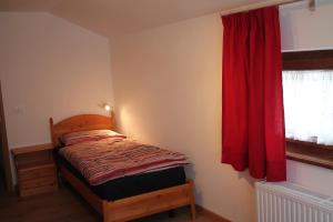 a small bedroom with a bed with a red curtain at Da Lisi in Ugovizza