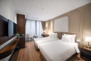 a hotel room with two beds and a television at L'amant de Hanoi Hotel in Hanoi