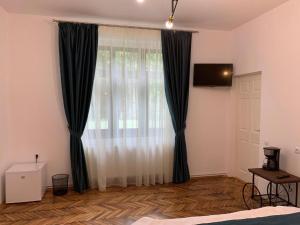 a bedroom with black and white curtains and a television at Margarethengasse Comfort Rooms Old Town in Sibiu