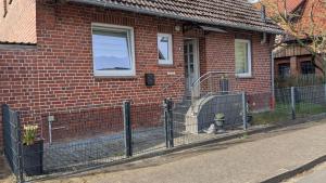 a brick house with a fence in front of it at Heideperle, Ferienhaus in Schneverdingen