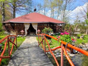 a wooden bridge leading to a gazebo in a garden at Pensiunea Emma in Sâmbăta de Sus