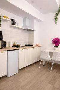 a kitchen with white cabinets and a table with purple flowers at Ametist in Mamaia