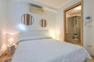 a bedroom with a white bed and two mirrors on the wall at L'Angolo Monolocale- Porto Torres in Porto Torres +13 photos