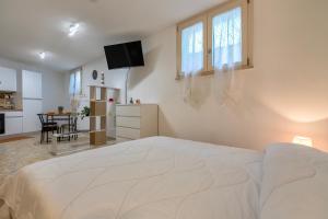 a white bedroom with a large bed and a table at L'Angolo Monolocale- Porto Torres in Porto Torres