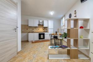 a kitchen with white cabinets and a table in a room at L'Angolo Monolocale- Porto Torres in Porto Torres