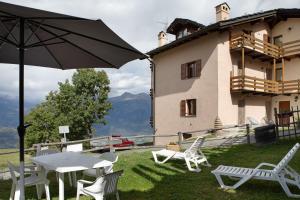 a patio with a table and chairs and an umbrella at Appartamenti Pila Vacanze 2 in Gressan
