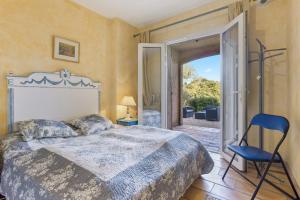 a bedroom with a bed and a chair and a sliding glass door at Villa - La Mignonette avec terrasse in Cavalaire-sur-Mer