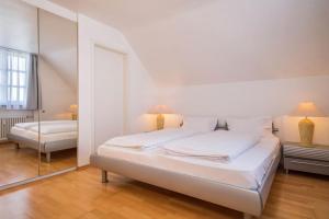 a white bedroom with a bed and a mirror at Appartement Rathausplatz in Kempten