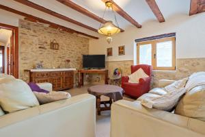 a living room with two couches and a tv at Lo Molí de la Jòrdia in Tortosa
