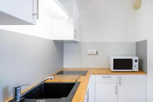 a small kitchen with a sink and a microwave at Les Mimosas - Appartement 07 in Cazaubon