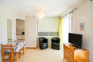 a living room with two chairs and a television at Les Mimosas - Appartement 07 in Cazaubon +12 photos