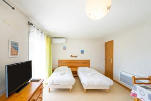 a room with two beds and a flat screen tv at Les Mimosas - Appartement 07 in Cazaubon