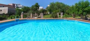a large blue swimming pool with trees in the background at Masseria De Donno in Specchia