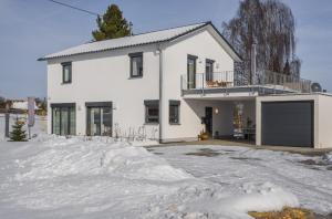 a white house with a driveway in the snow at Ferienwohnung Im Weiler, 70 Qm in Winterlingen