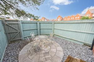 a patio with two chairs and a table and a fence at Dolphin Cottage - Short walk to Poole Quay with Private Garden in Poole