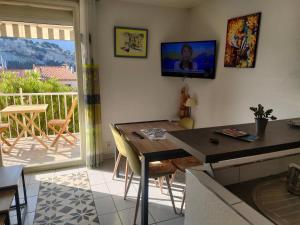 a living room with a dining room table and a balcony at T2 Le Bougainvillier Cassis in Cassis
