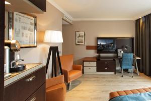 a hotel room with a tv and a living room at Hotel Dux in Roermond