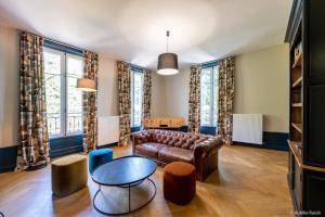 a living room with a leather couch and a table at Maison Bourgeoise de caractère in Tarare
